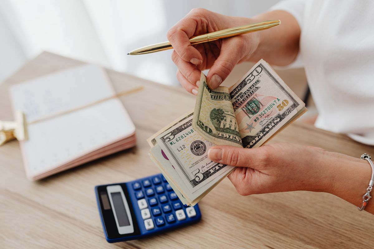 The image tells about a notebook, a calculator, and a girl's hand counting money referring to setting a fun cap by choosing the maximum amount per week instead of per month helps to set financial goals quickly.