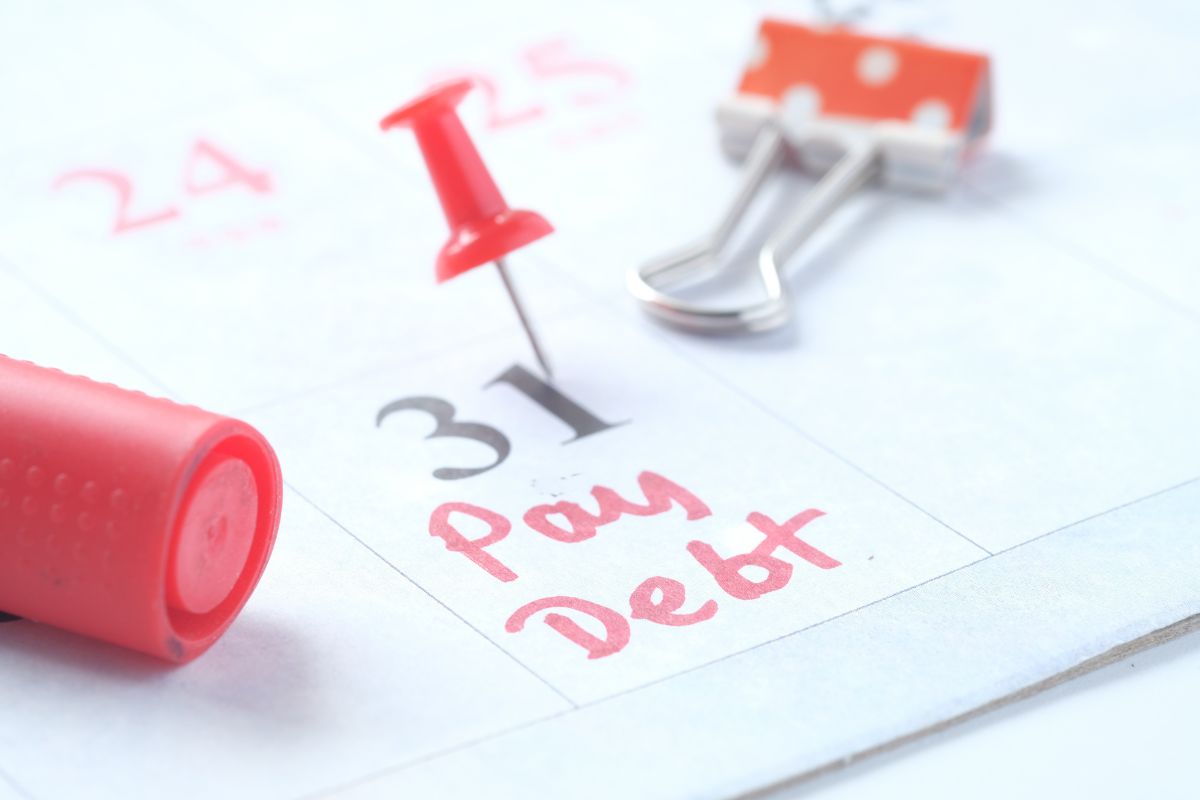 The picture of a calendar with notes on it, a pin, a marker, and a clip indicating how to pay down debt using the snowball and credit boost method gives you quick wins, also making sure your credit looks better to lenders.
