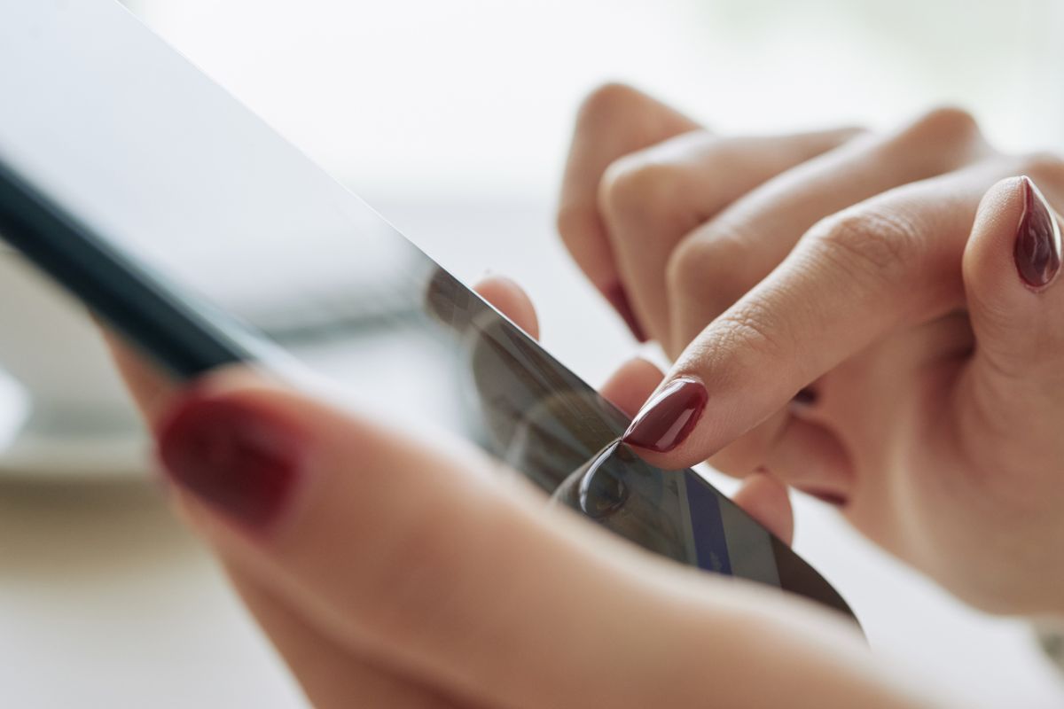 The photo of a woman's hand using a phone for cashback savings.