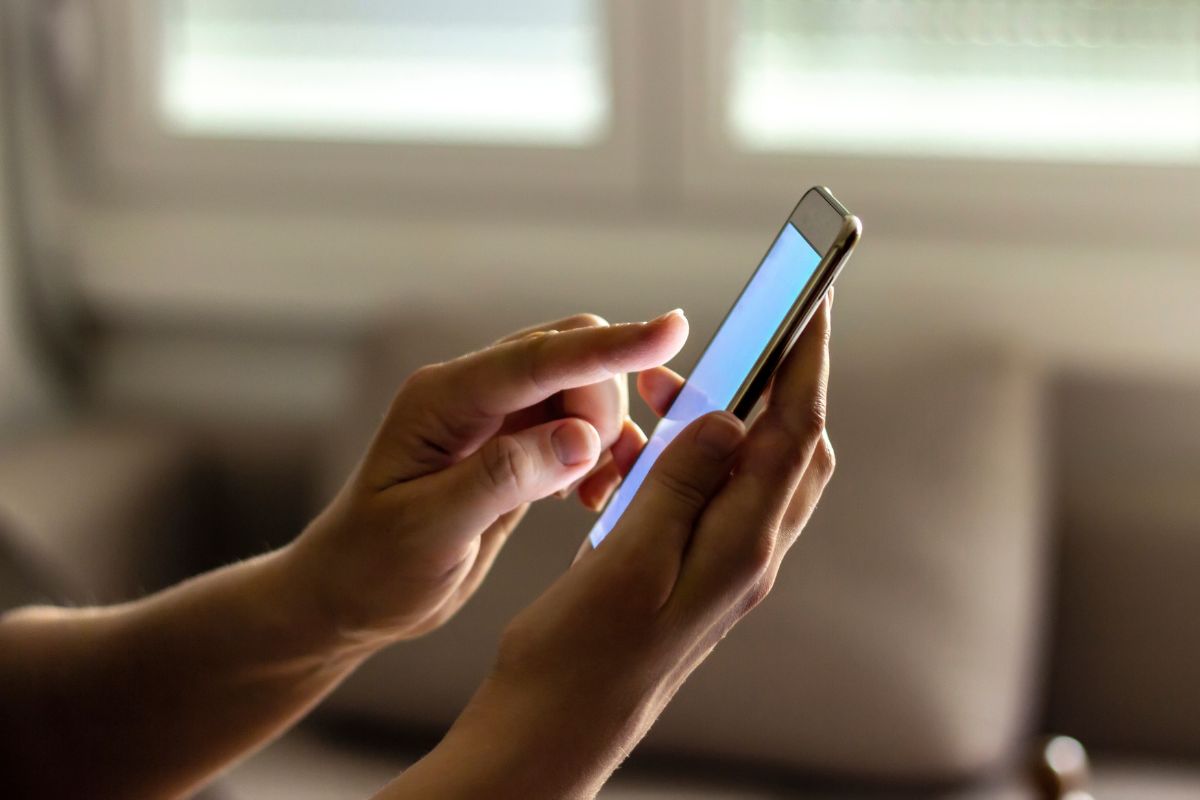The image shows a woman's hand using a phone to transfer money.