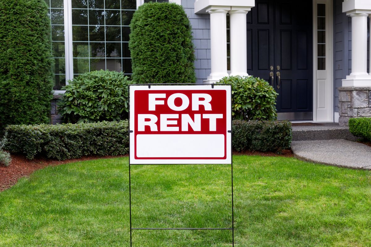 The image shows a house with signage referring to using home hacking or renting out part of your home to help lower your housing expenses and build wealth at the same time.