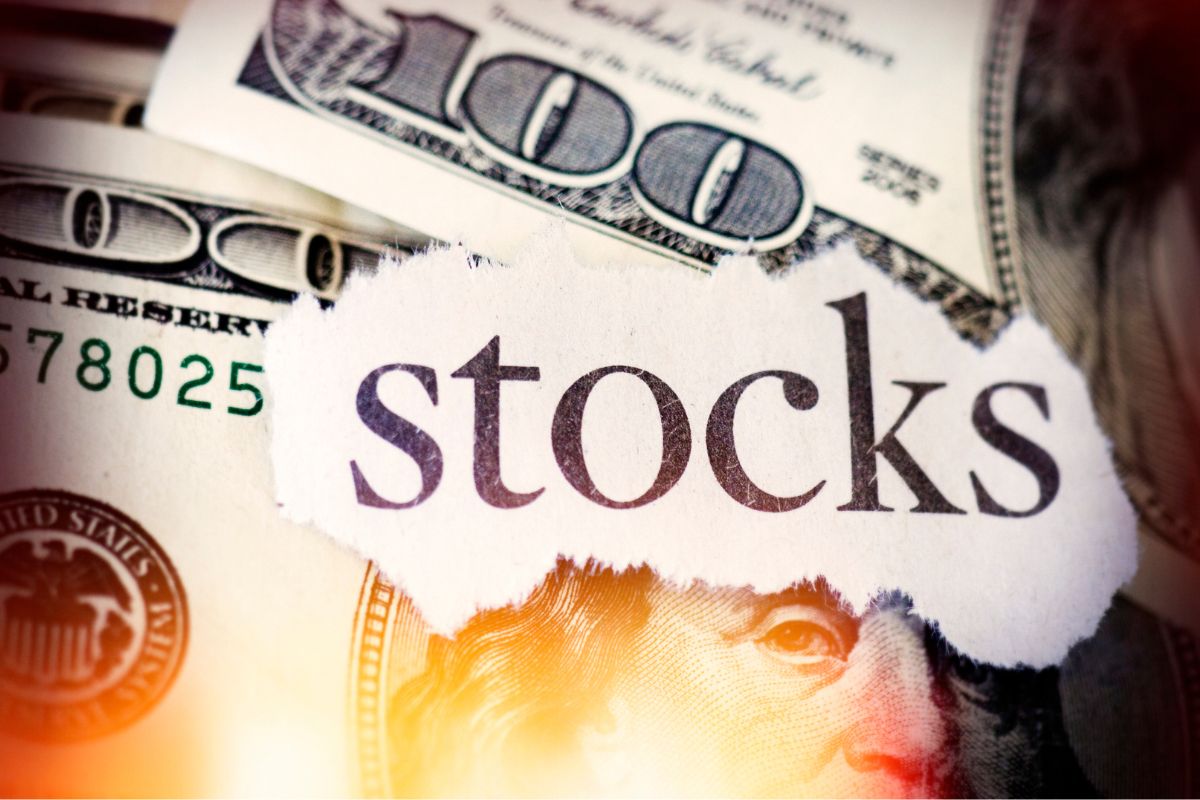 The photo shows money and a paper with stocks wording.