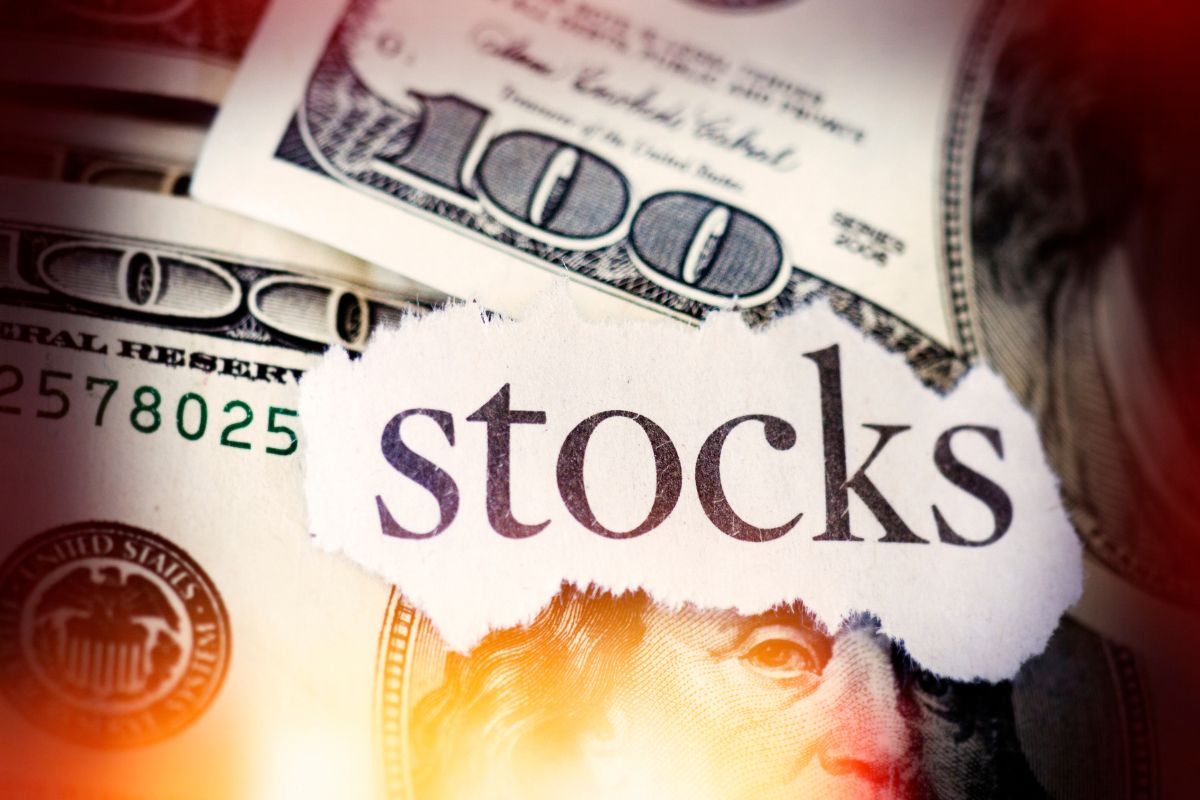 The image tells about dollar bills and a piece of paper with a note referring to capitalizing on buying undervalued stocks, those who buy low often end up much wealthier.