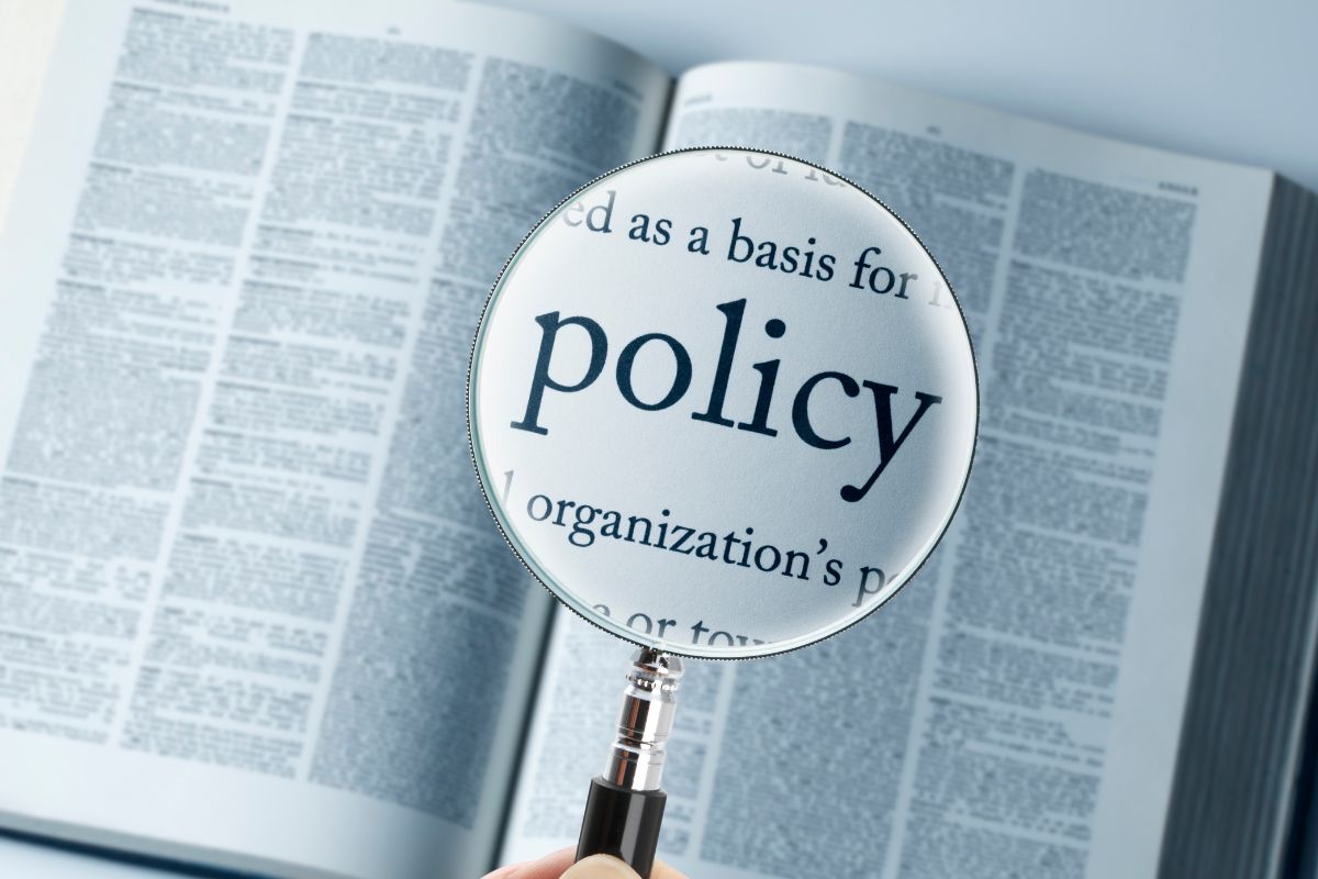 The picture shows a book a magnifying glass and policy wording.