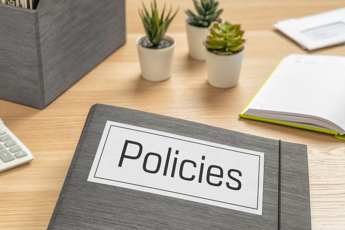 A photo shows a notebook with policies wording.