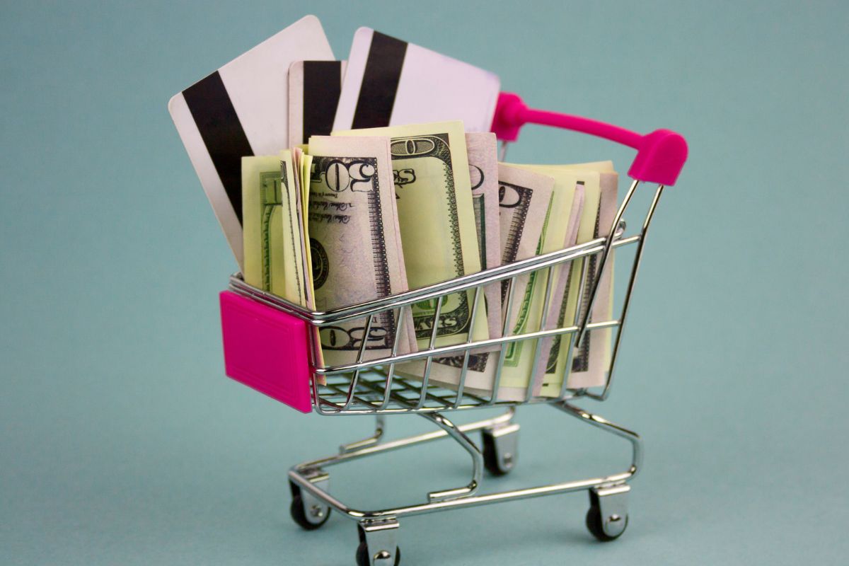 The picture of a cart, money, and credit cards for spending detox.