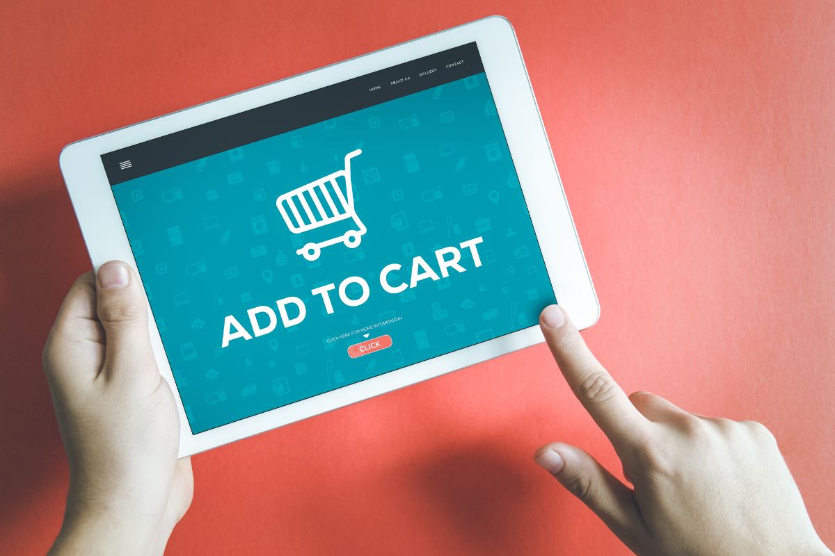 The image shows a girl's hand using a tablet device with a screen display which means that creating a fake shopping cart helps break the habit of impulse shopping.