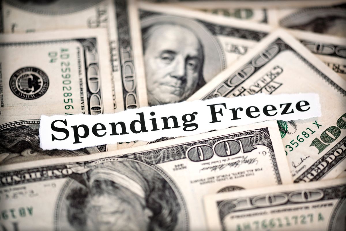 The picture tells about dollar bills and a piece of paper with notes which means setting spending-free zones makes it easier to cut back without feeling like you're giving up everything.