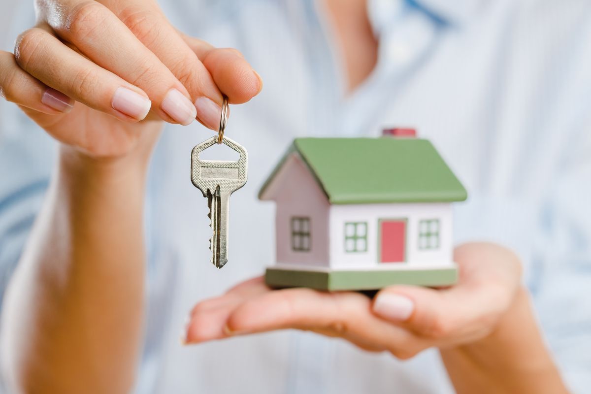 The image shows a woman holding a house and a key for a house sitter.