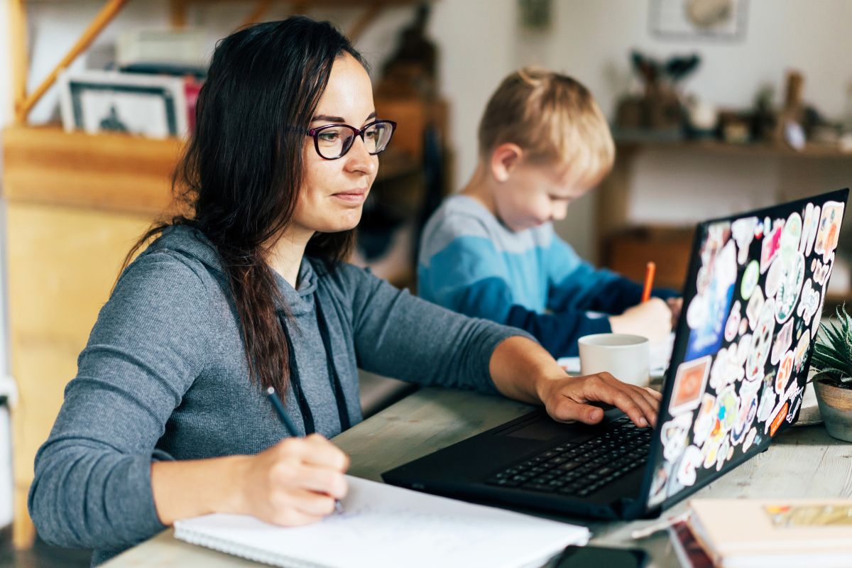 The image shows a woman working while taking care of her son.