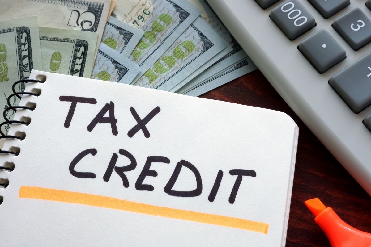 The picture of money and a notebook with tax credit wording.