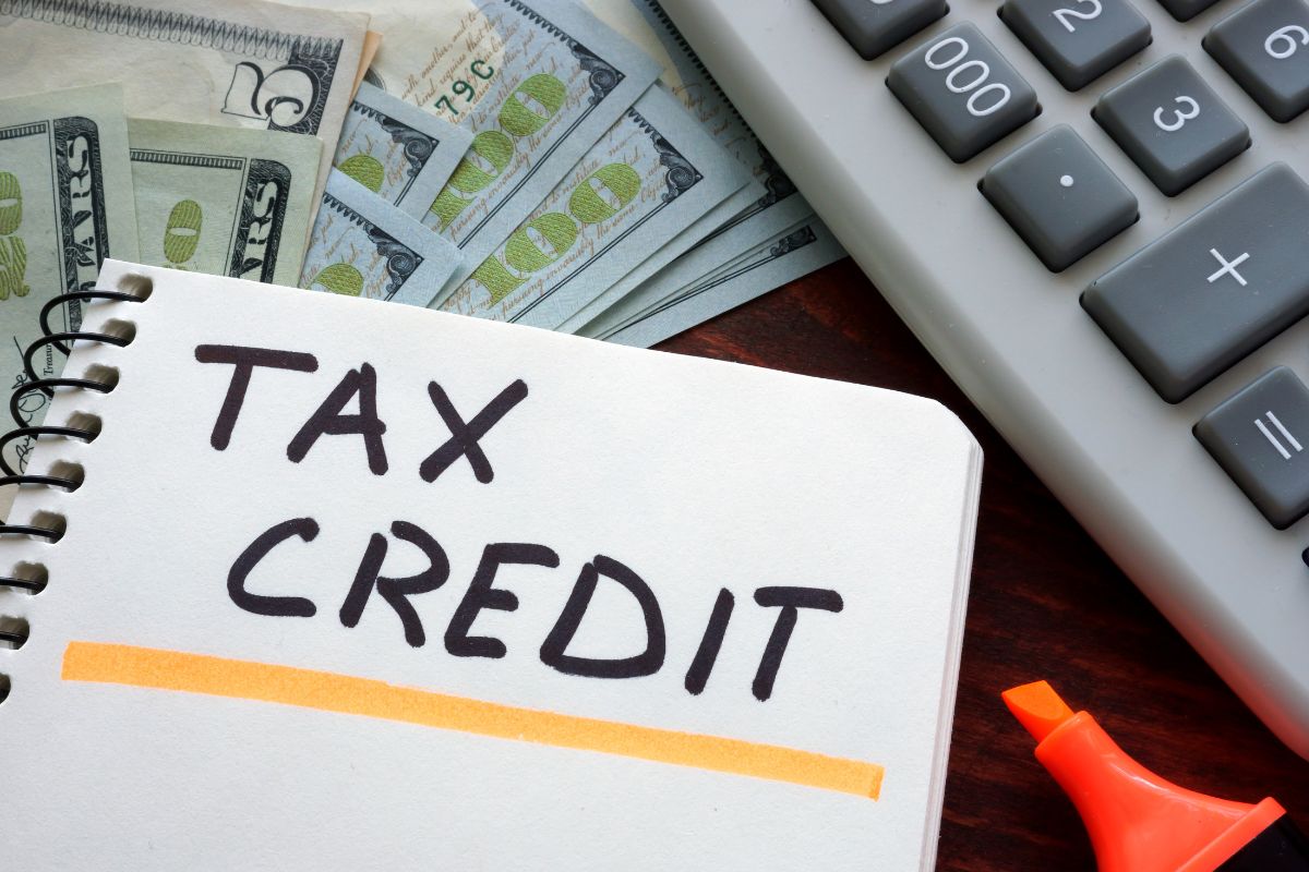 The image tells about dollar bills, a calculator, and a notebook with notes which means overlooking tax credits means paying more than necessary, checking it before filing can help keep more money in your pocket.