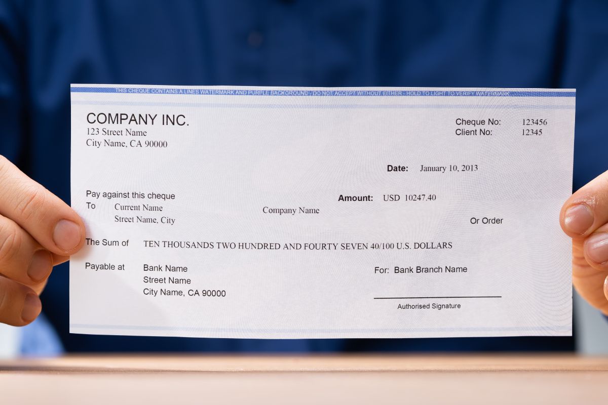 Image of a man's hand holding a paycheck.