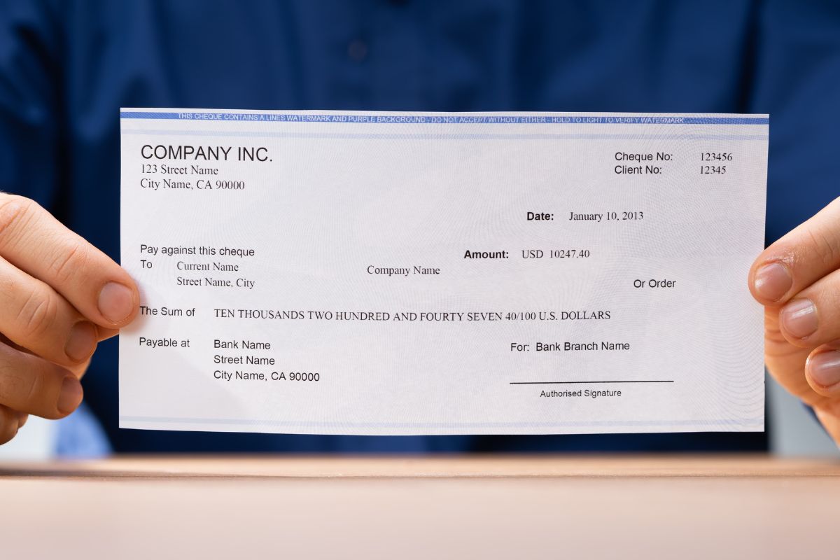The picture shows a man's hand holding a piece of paper with notes which means withholding too much from paychecks you're missing out on money you could have used throughout the year.