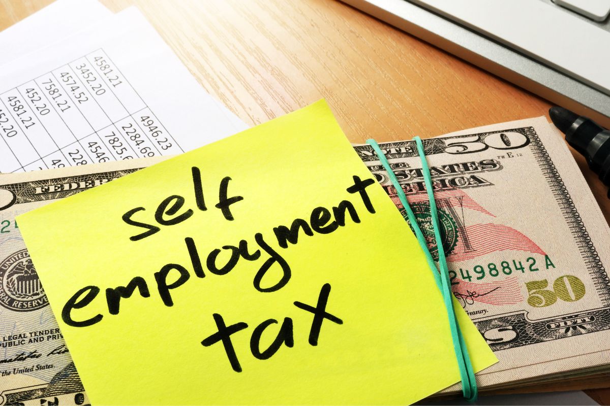 The picture of money and a paper with self-employment tax wording.