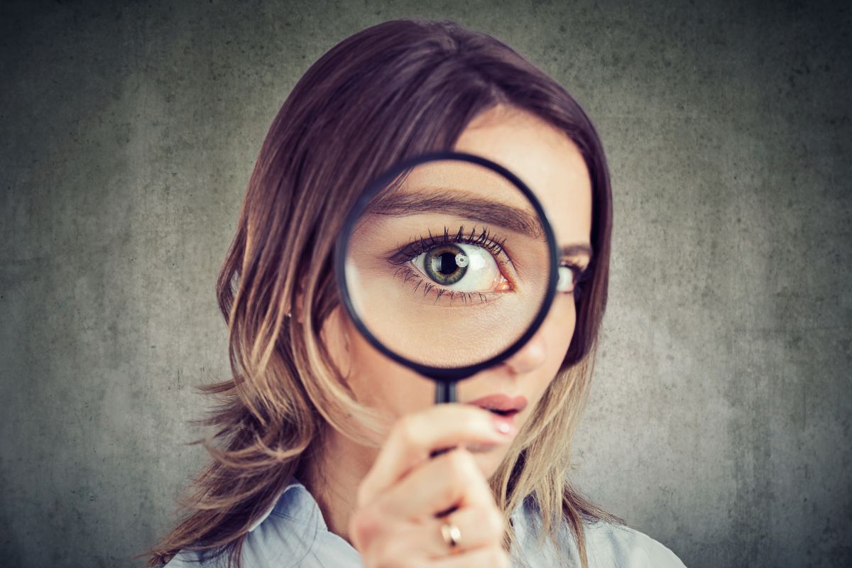 The image shows a woman using a magnifying glass.