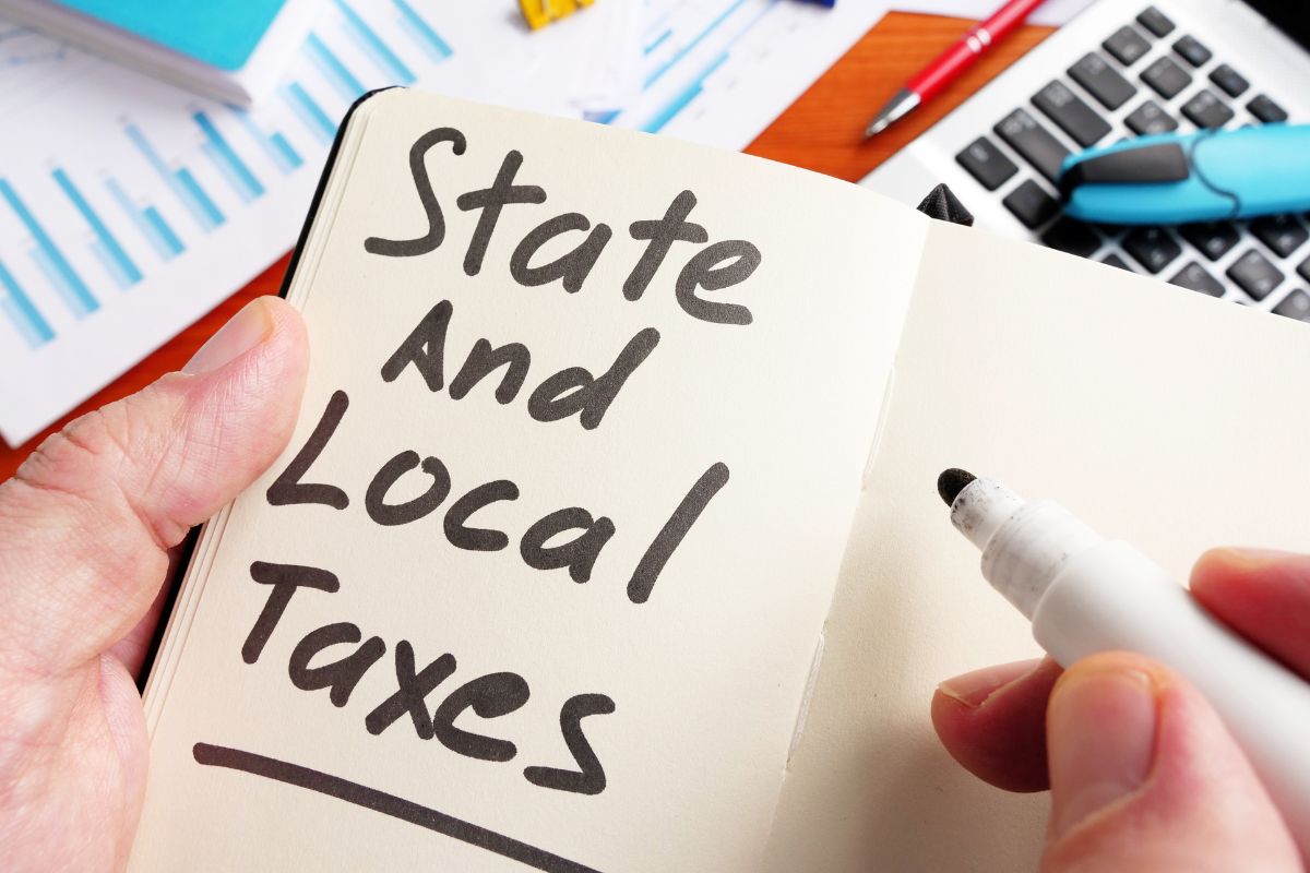 Picture a woman's hand and write state and local taxes in a notebook.