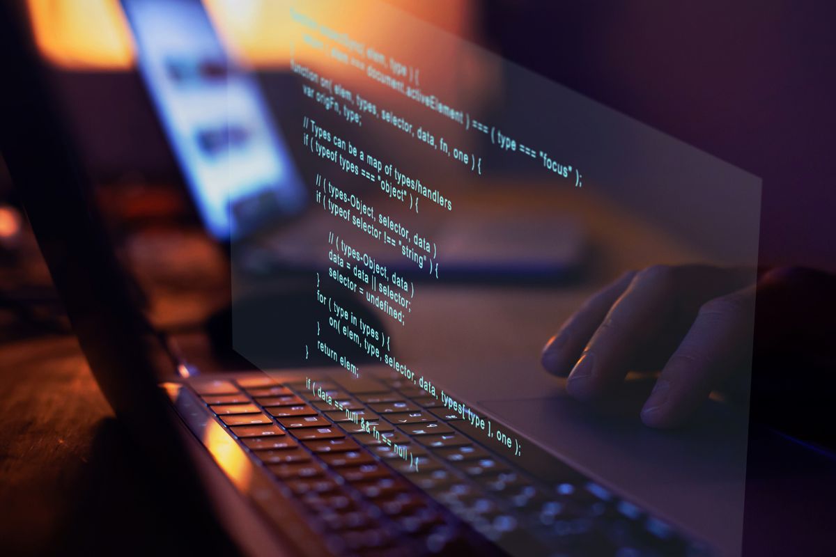 The photo shows a man's hand working on software development.