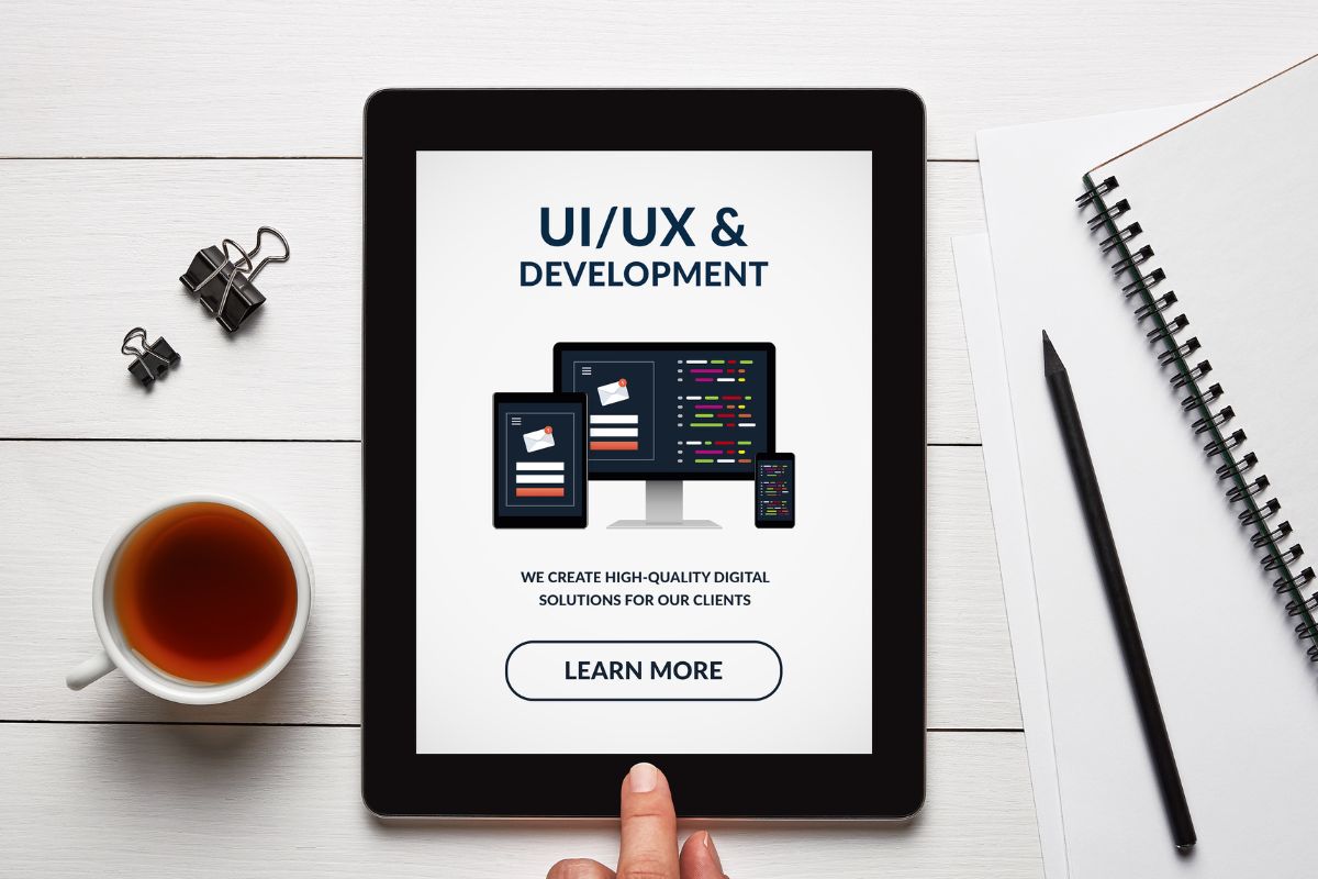 The photo of a woman's hand holding a tablet with UI/UX design.