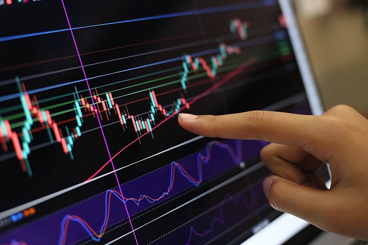 The picture shows a girl's hand pointing the screen with a graph which means investment management and day trading help you grow your money and wealth.