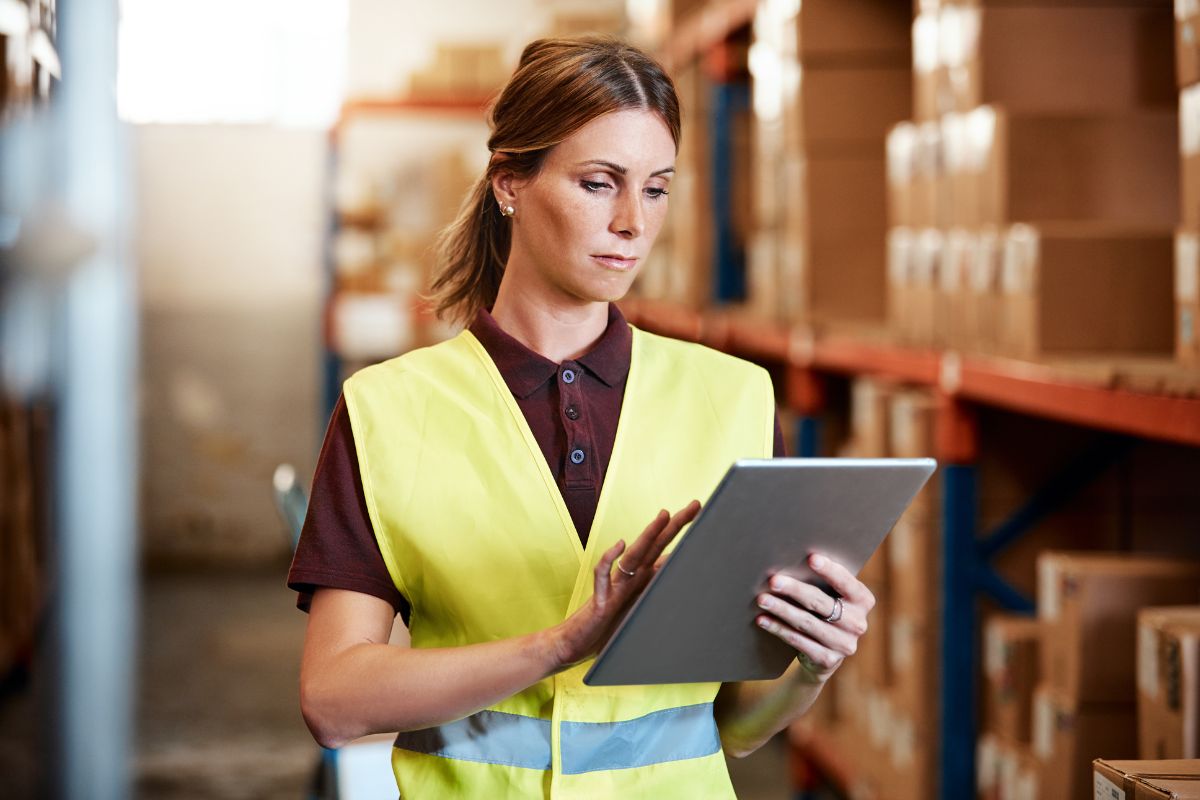 The image shows a girl using a tablet device with boxes behind referring to a supply chain and logistics management which a process of moving product distribution is one of the in-demand skills that helps you grow your income.