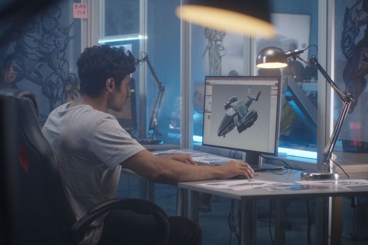 The picture shows a man using a computer while editing on the subject which means 3D modeling is an in-demand skills that process the 3D representation of a project that can make money with digital arts.