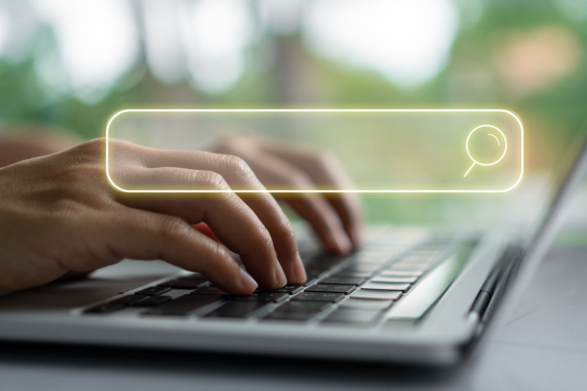 The photo shows a girl's hand typing on the laptop with a search icon on the screen referring to finding the top high-income skills without a degree and turning your passion into money and earning a high paying job.