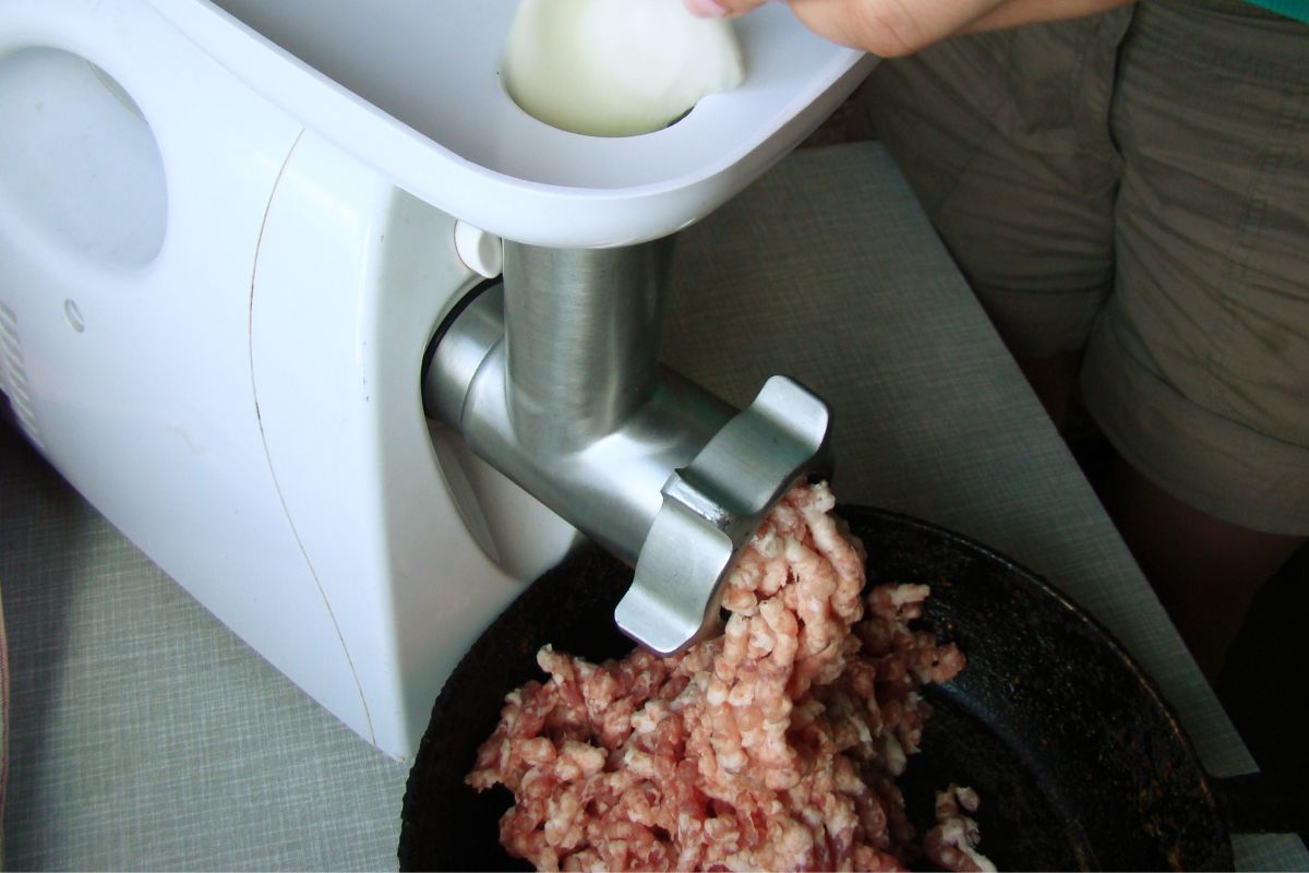 Photo of a man grinding his own meat.