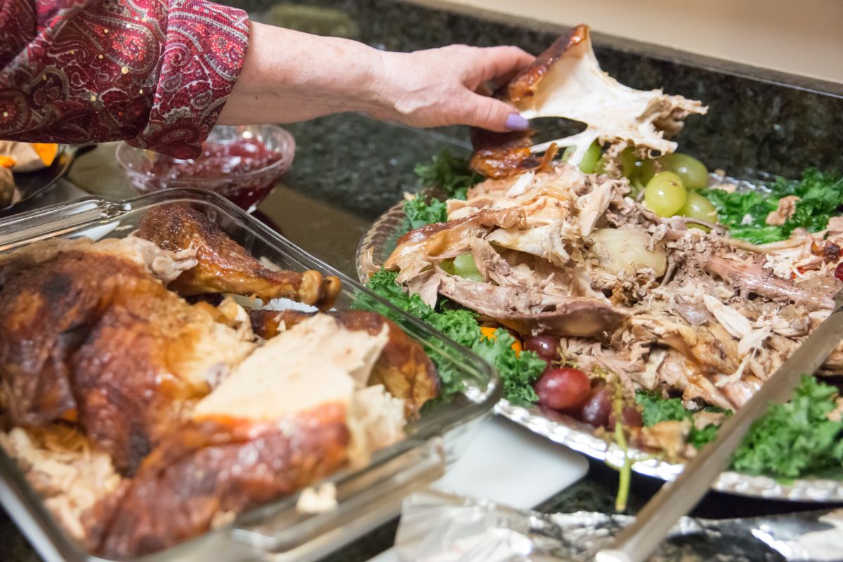 The photo shows a girl's hand holding a glass tray and picking up meats which means that turning leftovers into new meals is a simple habit that saves money and makes meal planning easier.