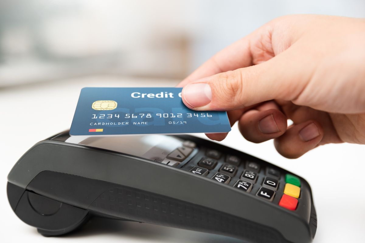The picture shows a girl's hand tapping the credit card on the swiping machine referring to the use of credit cards strategically to earn cashback and rewards on things you were already going to buy.