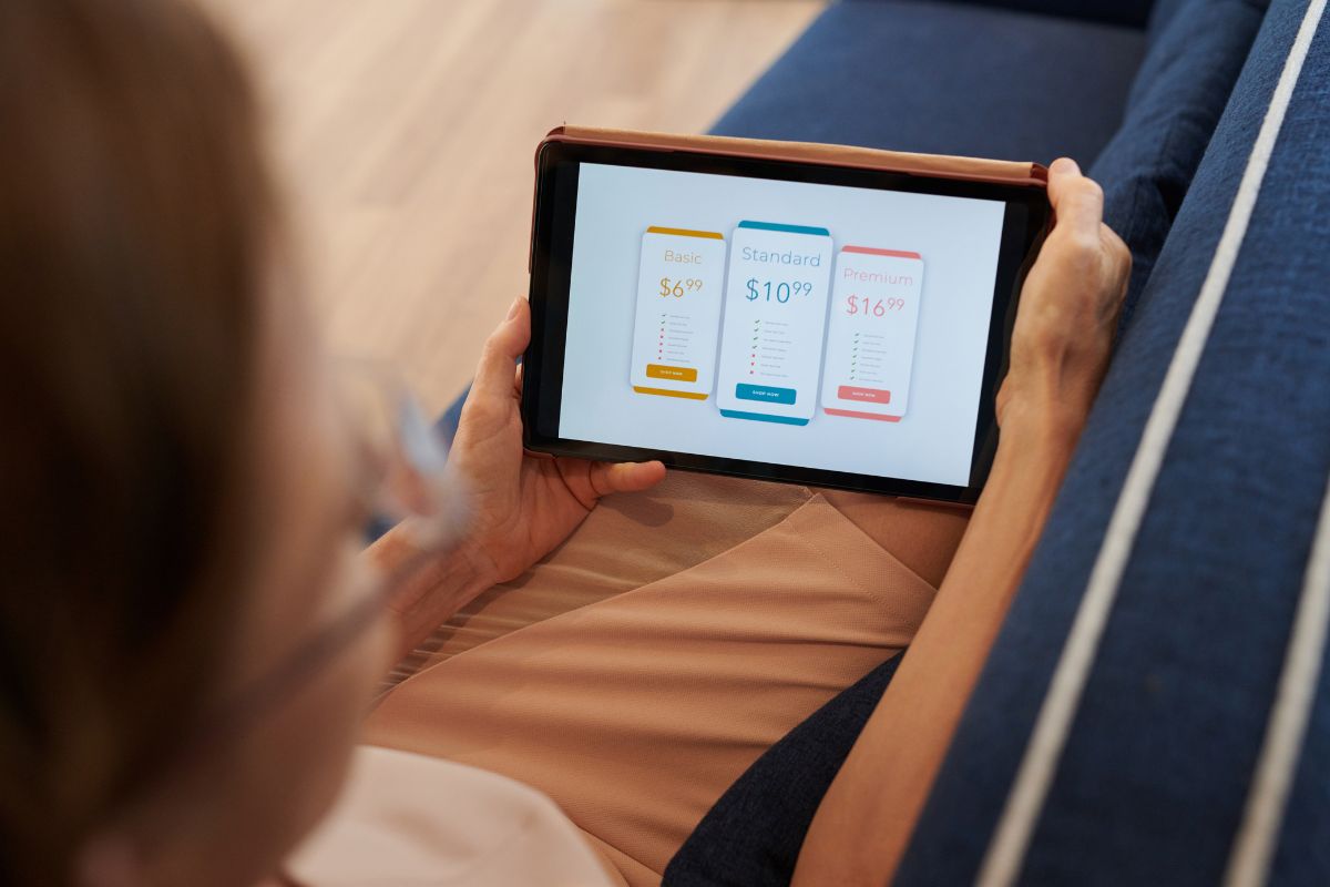 The picture shows a girl holding a tablet device with a screen display which means eliminating useless subscriptions and cutting them out means more money for savings and investing.
