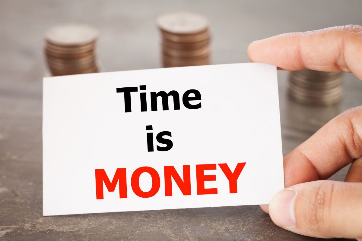 The image of a man's hand holding a paper with time is money written.