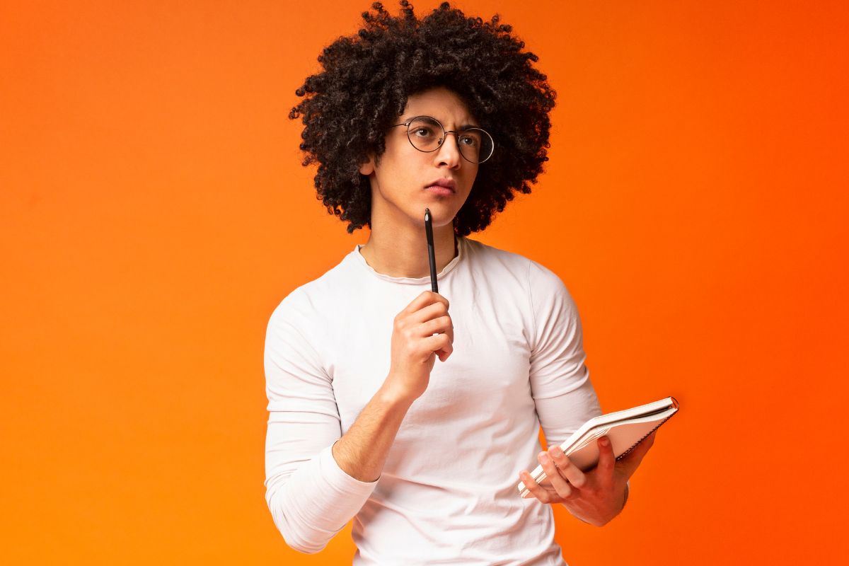 The photo shows a man holding a notebook while thinking which means that setting up financial speed bumps helps you avoid regret and more control you have over your spending.