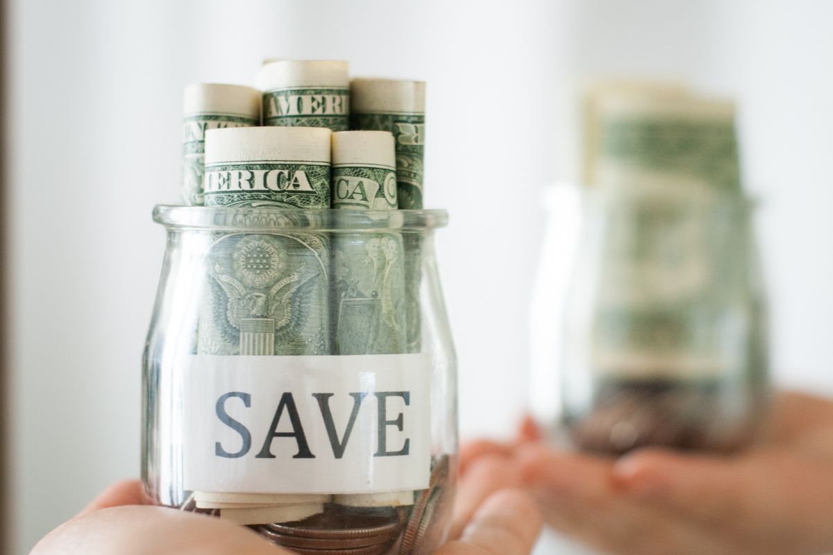 Picture of a woman's hand holding a jar of savings.