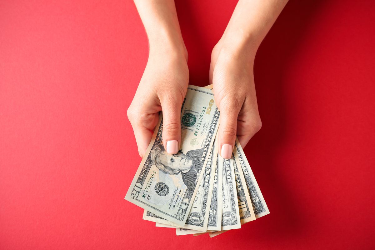 The photo shows a woman's hand holding money.