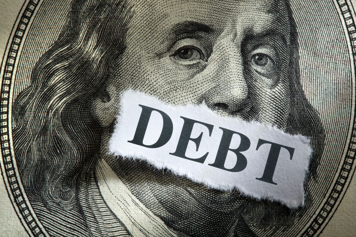 Image of a money and paper with debt wording.