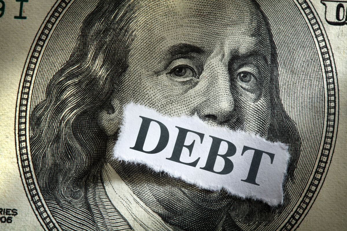The picture tells about dollar bills and a piece of paper with a note which means to use the debt as fire mindset helps you stay focused on being debt-free sooner.