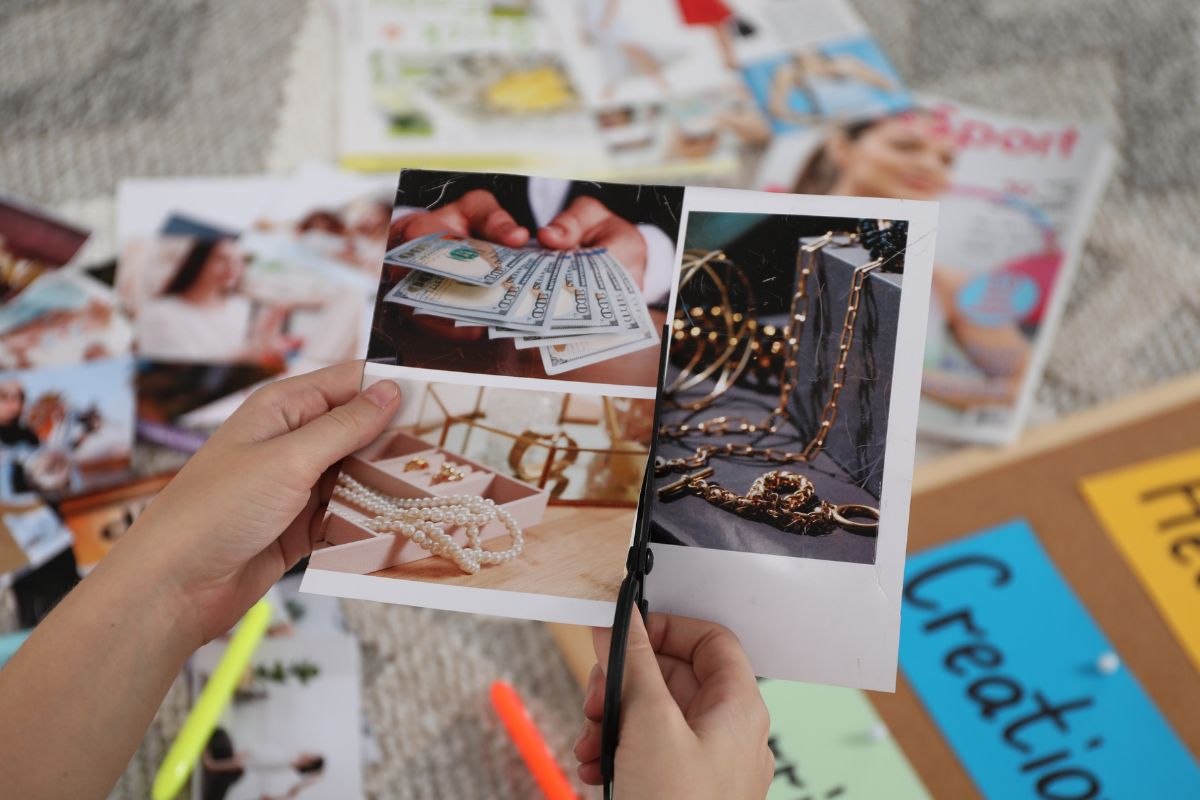 The picture of a woman's hand creating a vision board.
