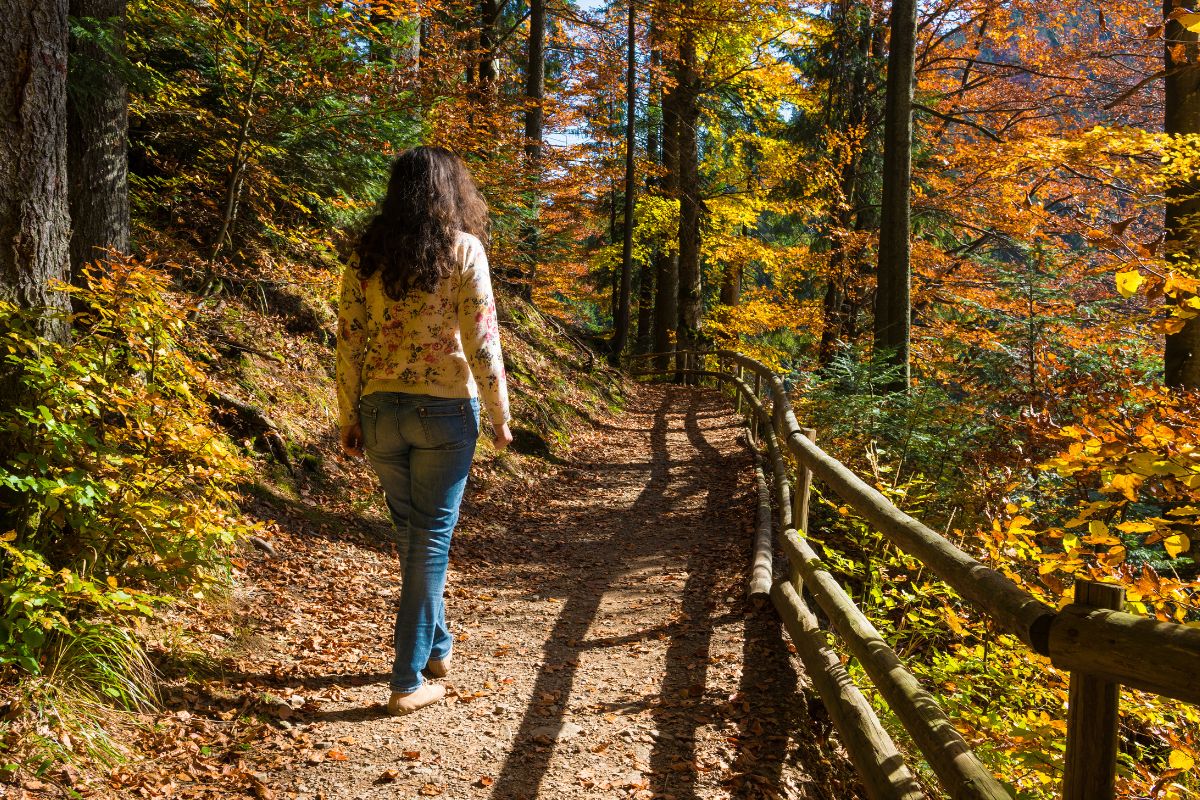The image of a woman walking by the trees.