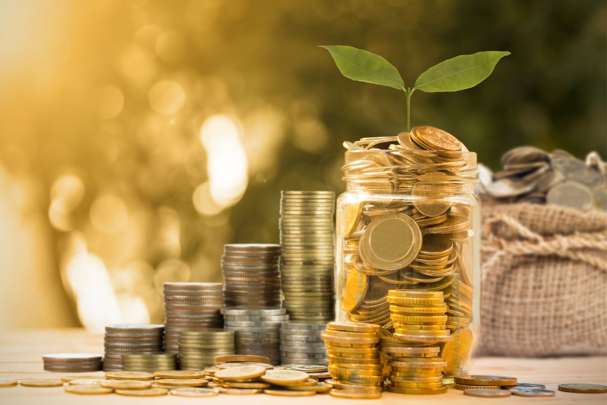 The image tells about coin stocks, a bag with coins, and a jar filled with coins and with a plant referring to the Pick a Money savings challenge keeps you motivated and makes it easier to stick with it.