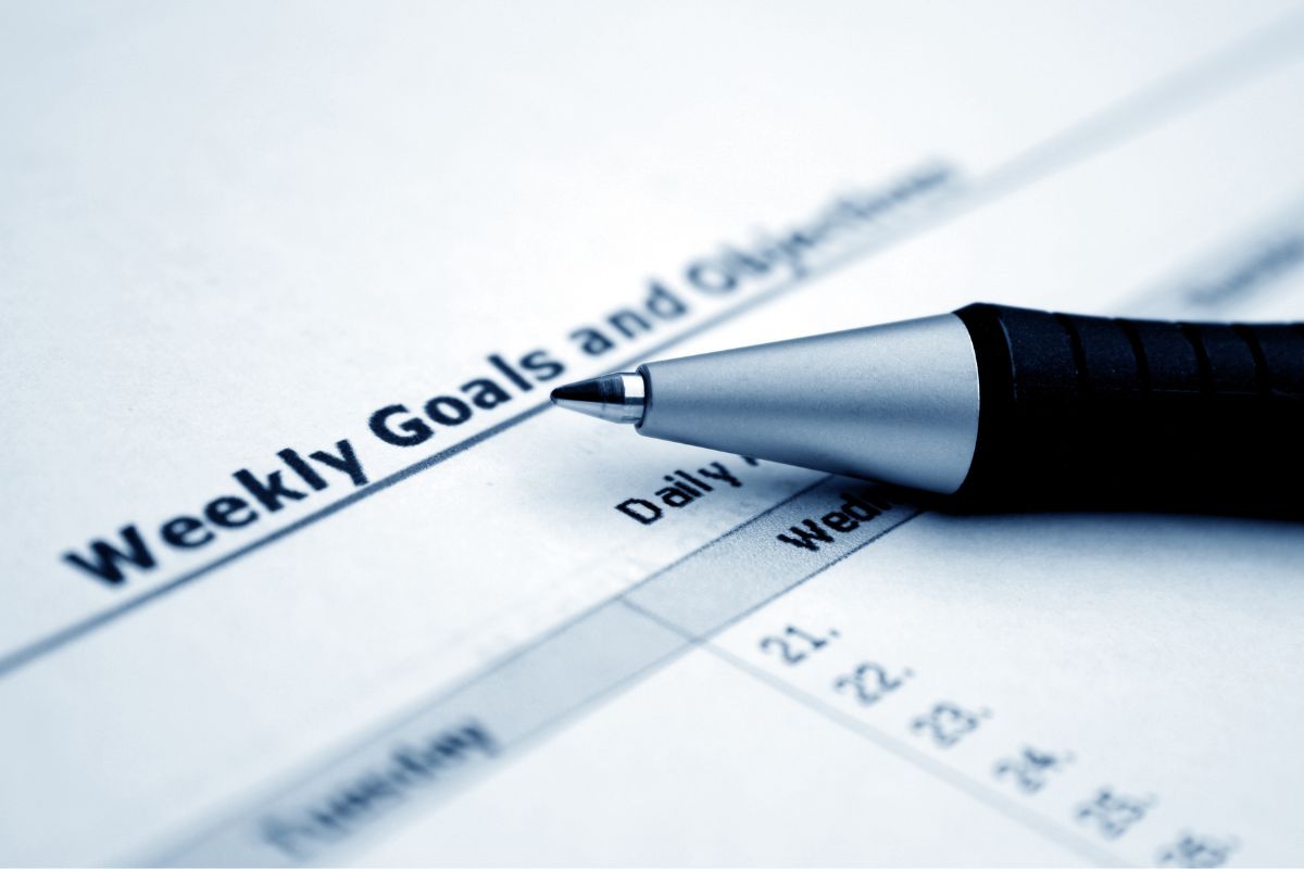 Image of a pen and a piece of paper with weekly goals written.