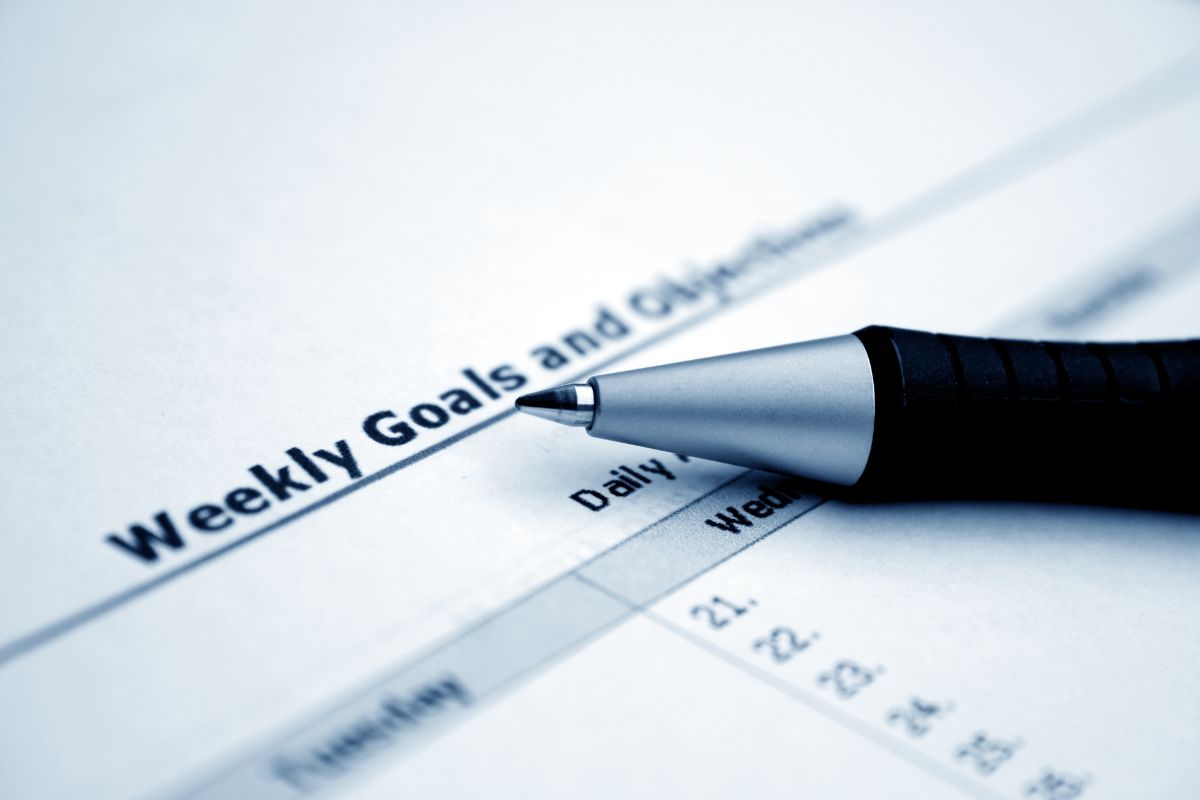 The photo shows a pen and a piece of paper with notes referring to reverse-engineering your goals to keep you on track which leads to big financial success.