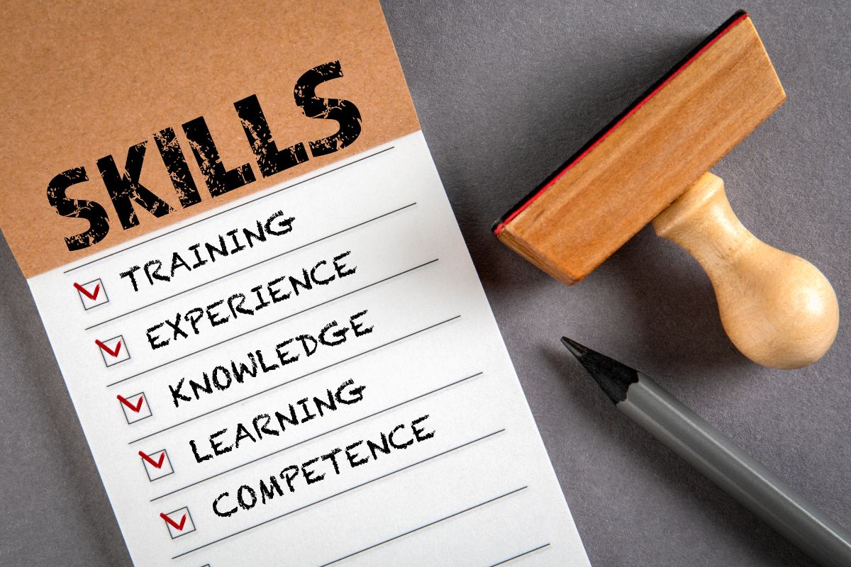 The image shows a stamp, a pen, and a piece of paper with notes indicating to learn the skills you need right now to build your knowledge and get closer to your dream job.