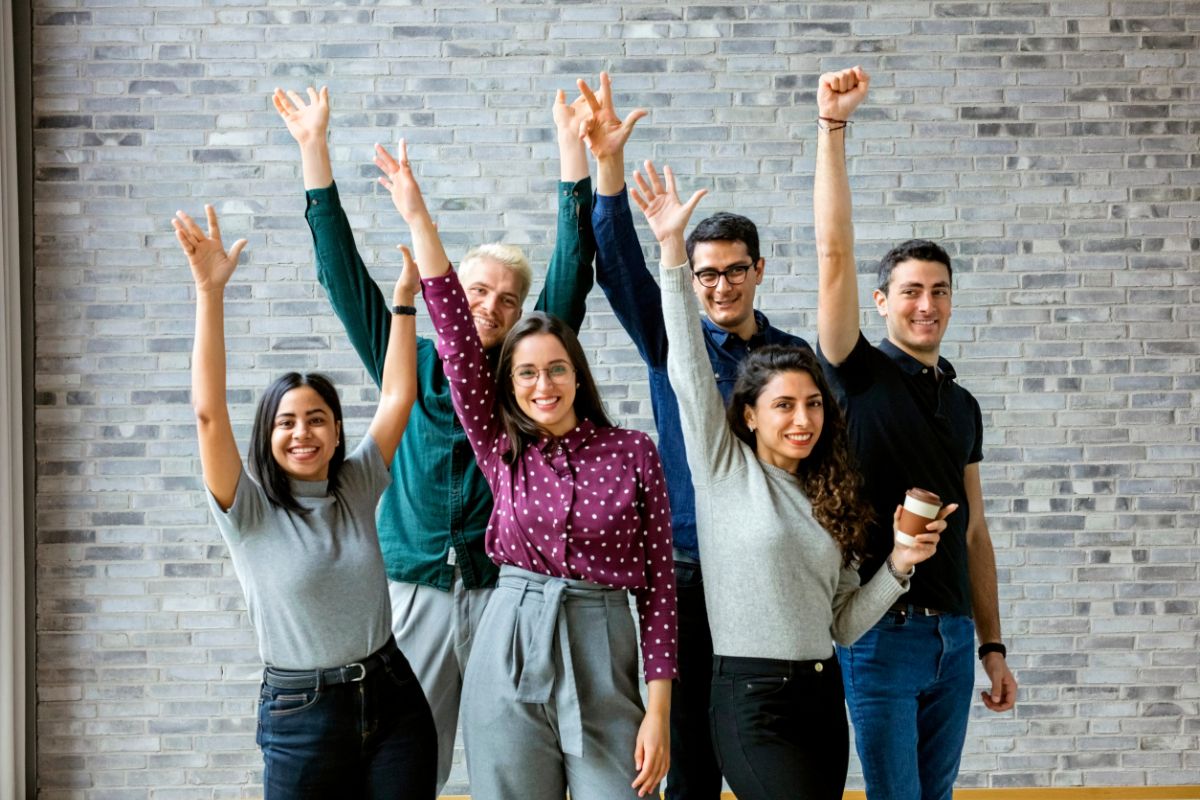 The picture shows a group of people raising hands together which means that surrounding yourself with successful people puts you in the right place for new opportunities.