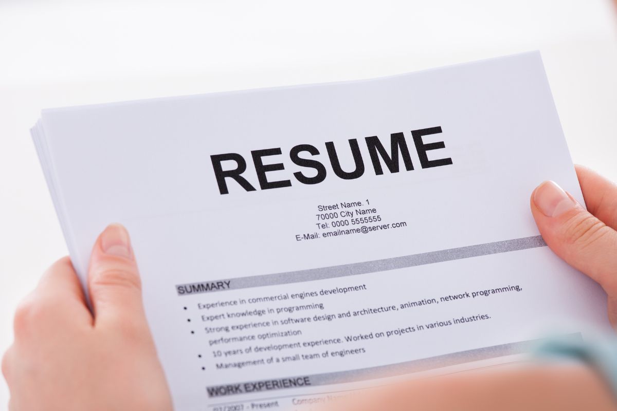 The image shows a woman's hand holding a paper of resume.