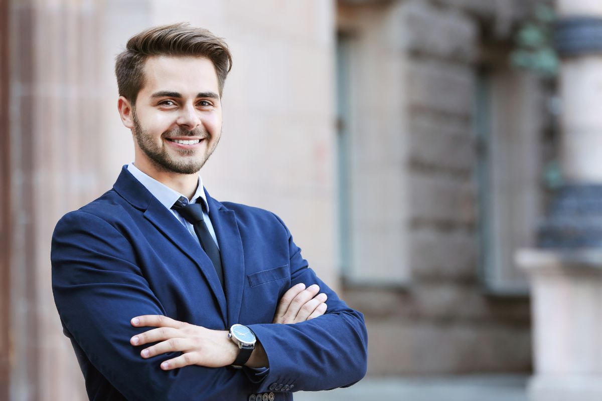 The photo shows a man in a suit smiling which means acting like you already have the job helps you feel more comfortable in interviews and networking events.
