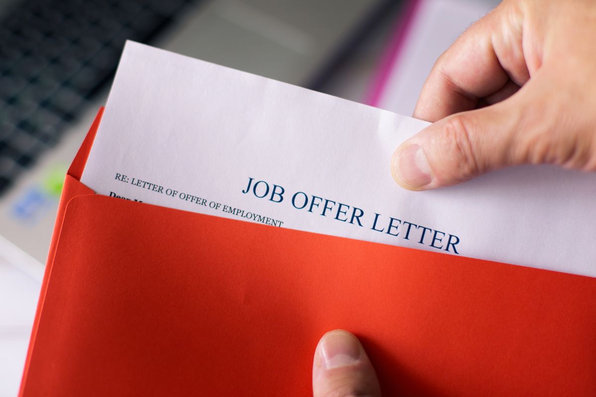 The image shows a man's hand opening the red envelope with a piece of paper with notes referring to how being open to unexpected job offers leads to better jobs and more money.