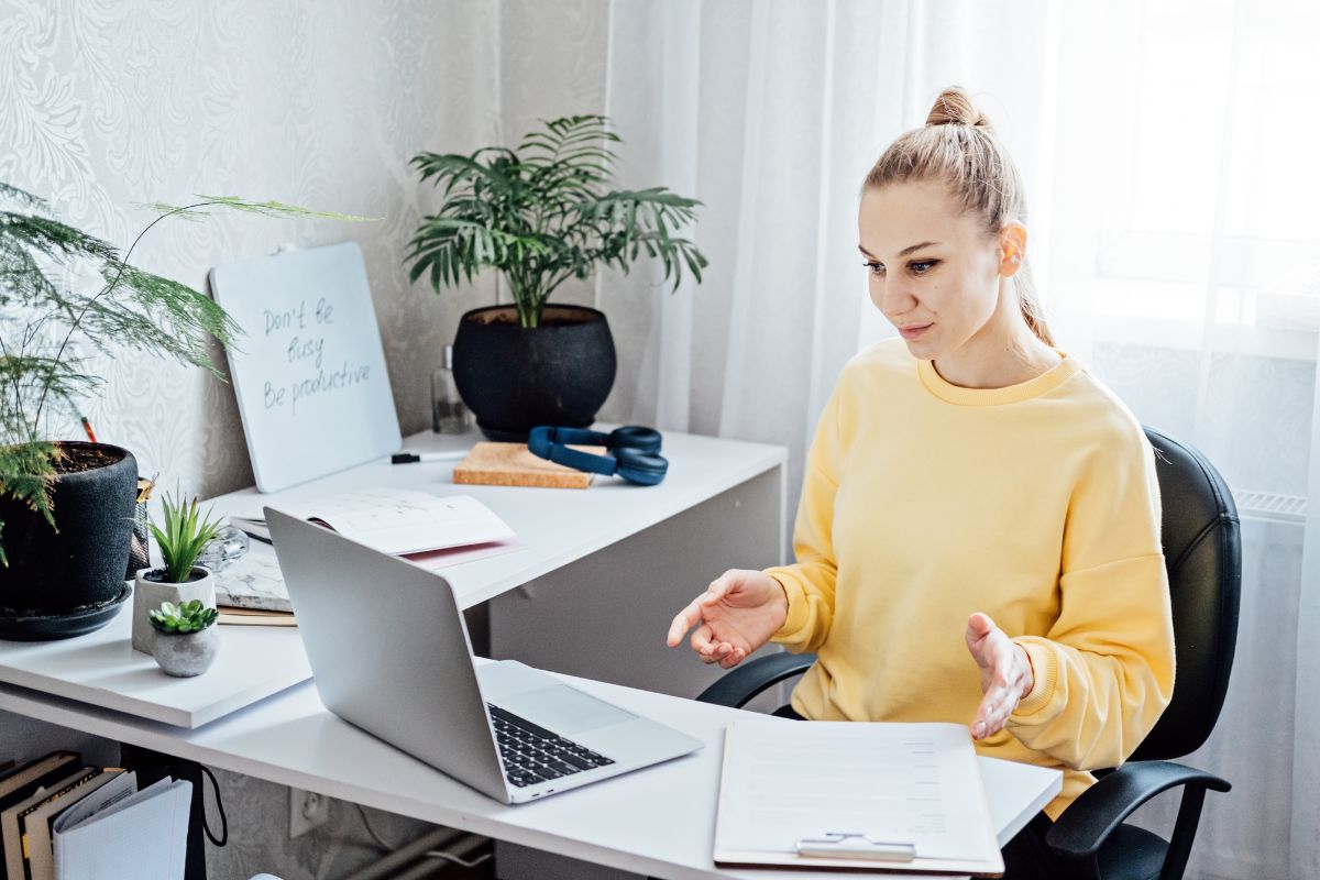 The photo shows plants, a clipboard on the table, and a girl looking at the laptop referring to a one-week side hustle sprint to help earn extra income and make it easier to reach $500 fast. 