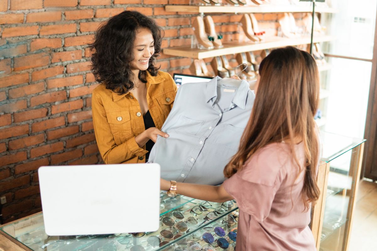The image shows a laptop and a girl showing the shirt to the cashier which refers to returning recent unnecessary purchases as a fast and effortless way to get cash back.