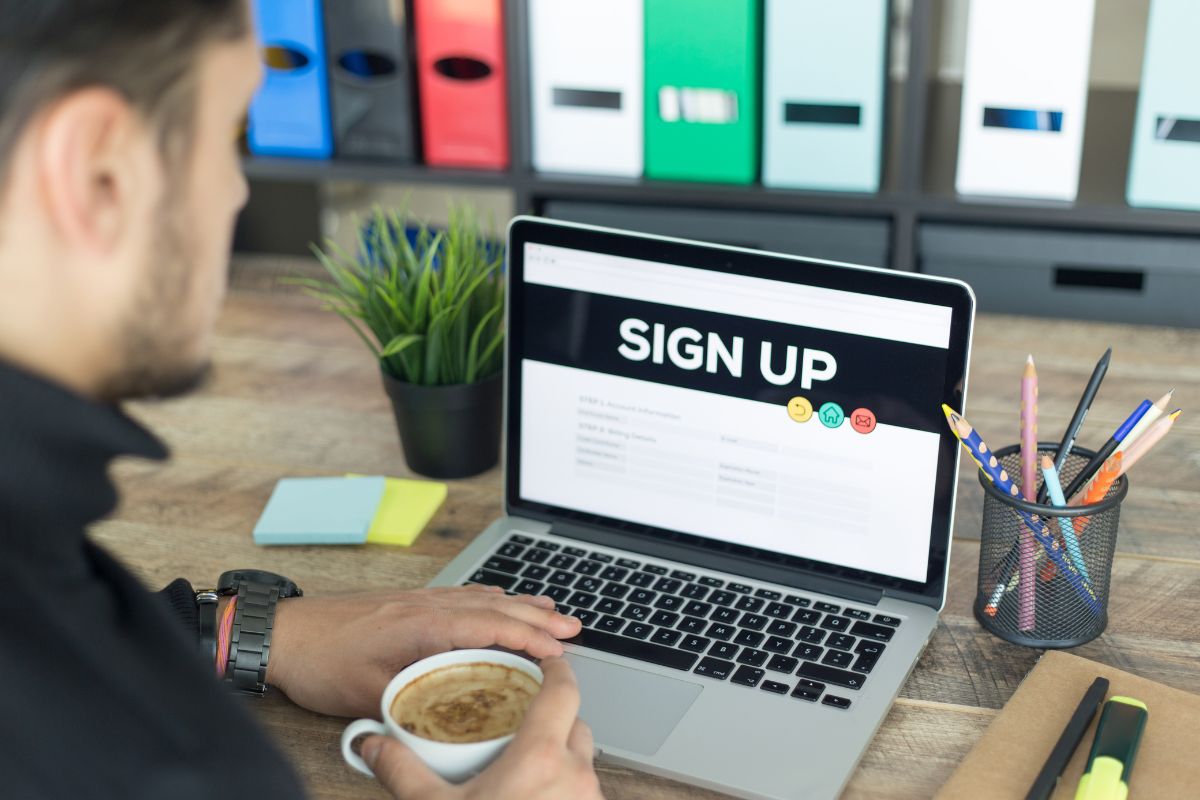 The image tells about pens, a plant, and a man using a laptop with a screen display while having a coffee which means getting paid for odd jobs is the fastest way to earn extra cash.